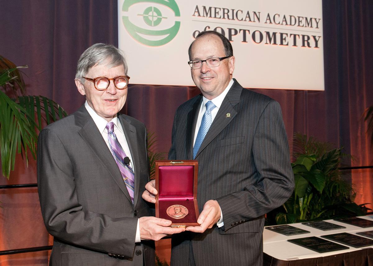 Gordon and AAO President Bernard Dolan both wearing suits, holding the Prentice Medal between them.