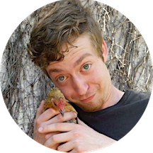 Andrew holding a chicken next to his face.